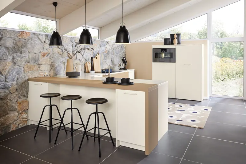 Cuisine blanc laine et beige caramel devant un mur en pierre